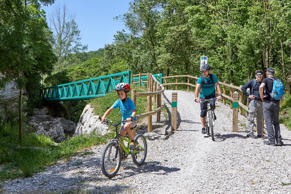 Adulto y  niño y detrás una paserla de la vía verde del Plazaola